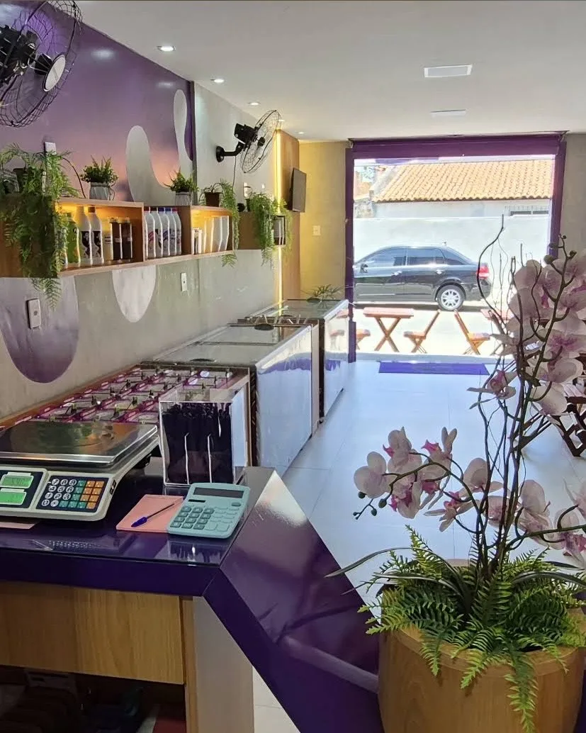 Balcão roxo com balança, freezers e plantas ao fundo