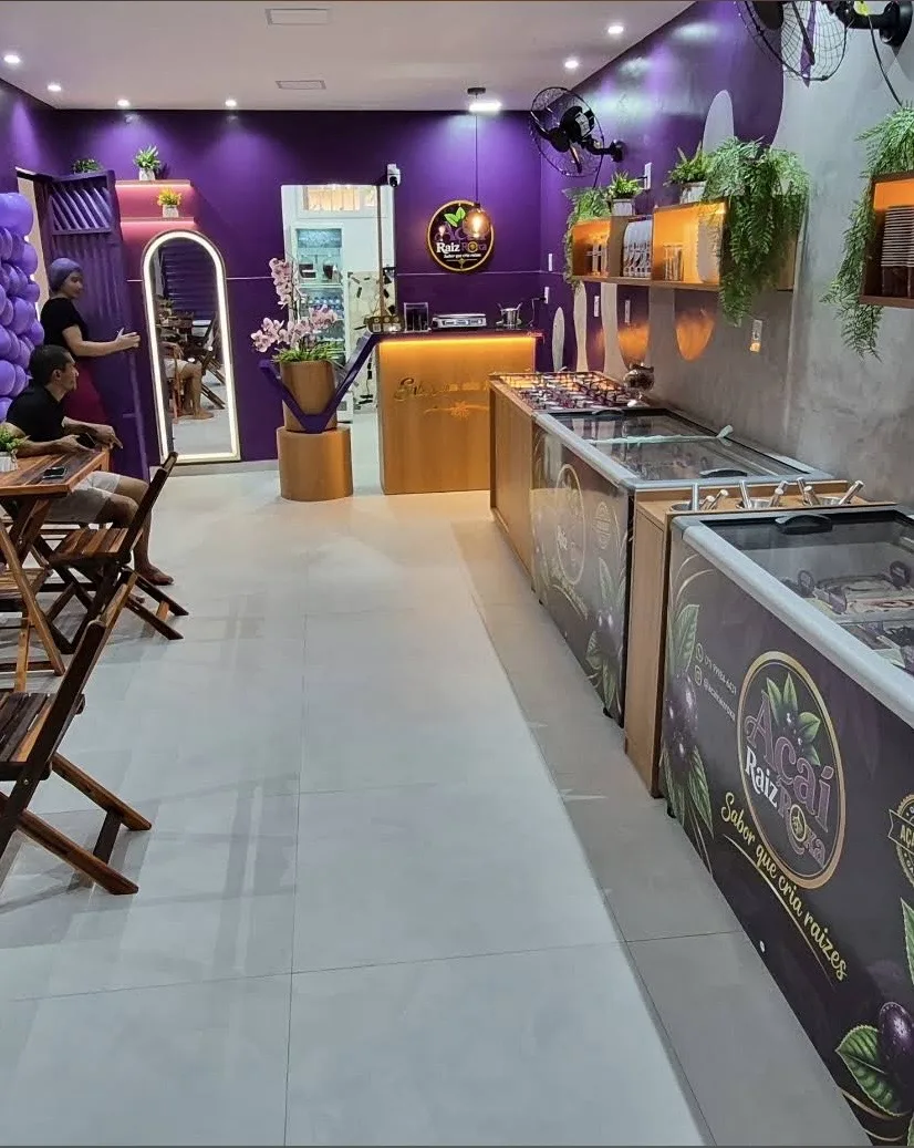 Interior da loja Açaí Raiz Roxa com paredes roxas, balcão de madeira e freezers de sabores